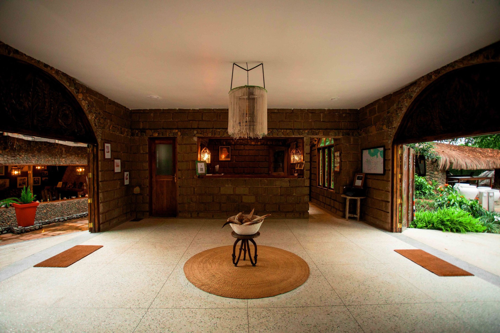 Stone lobby entrance with beaded chandelier and arched doorways at Mtoni River Lodge