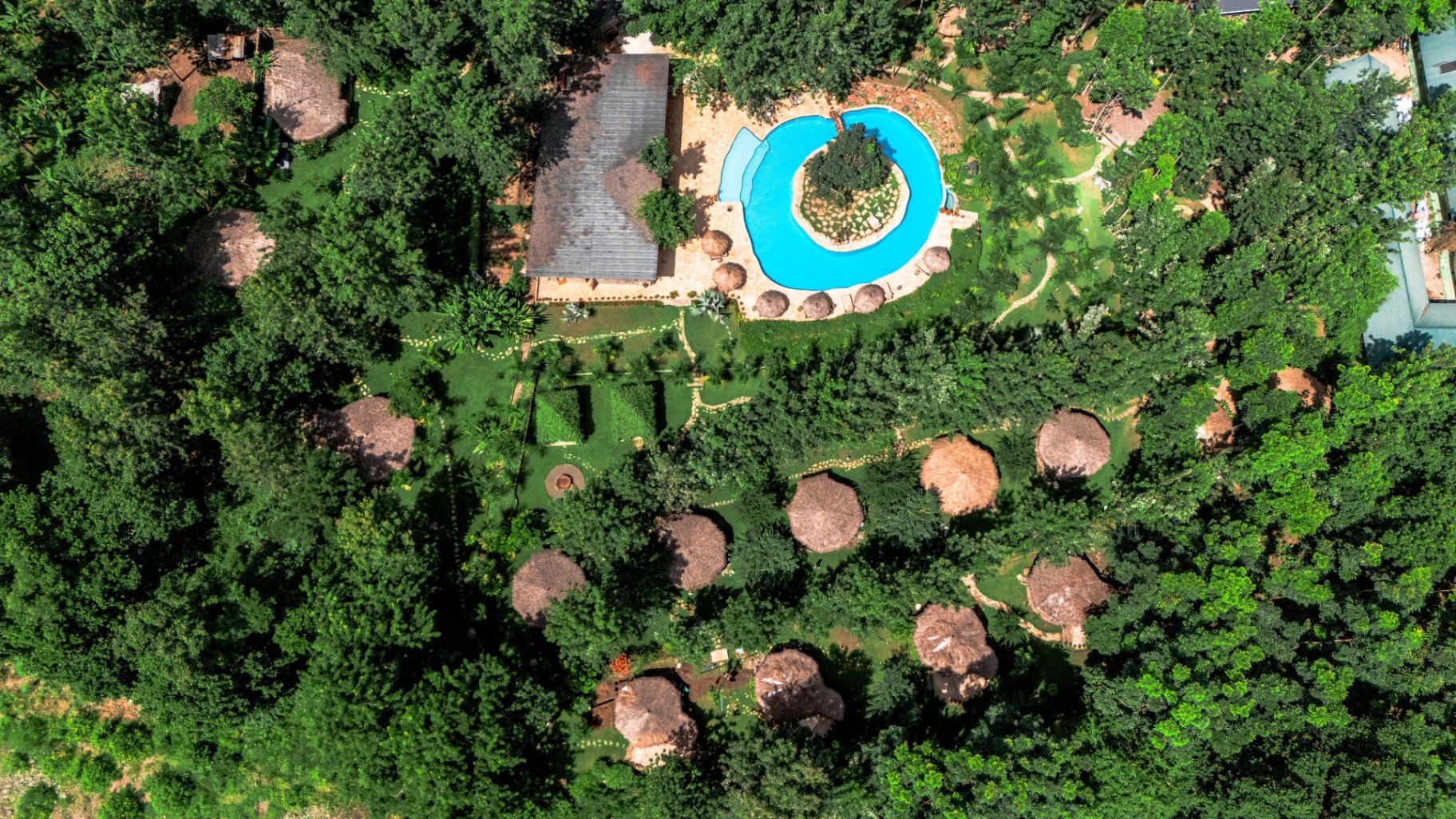 Aerial view of Mtoni River Lodge — thatched villas nestled among the forest canopy