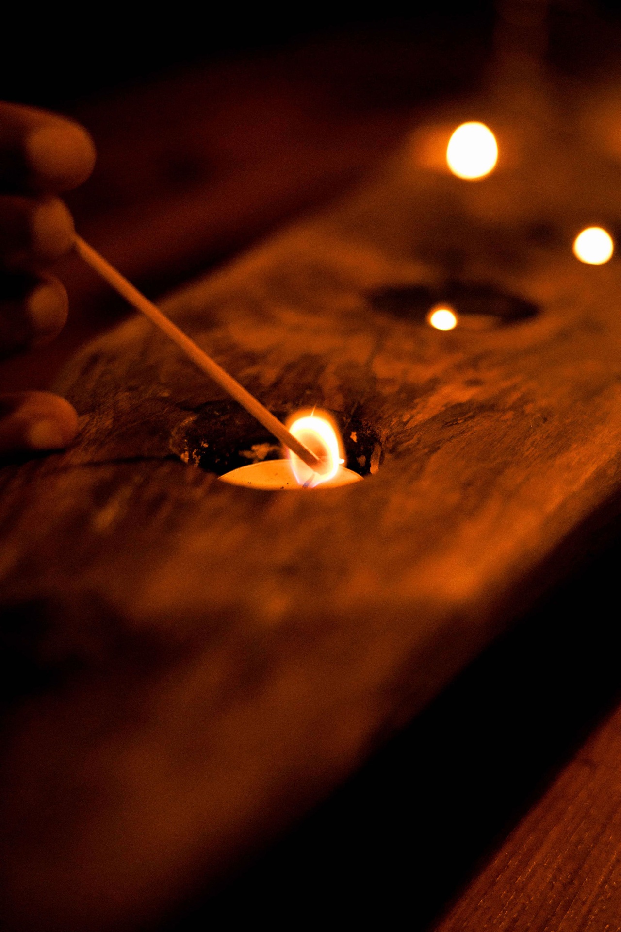 Hand lighting a candle by firelight — an evening ritual at the lodge